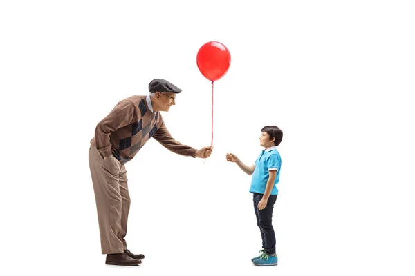 Senior man giving a red balloon to a child — Stock Photo, Image