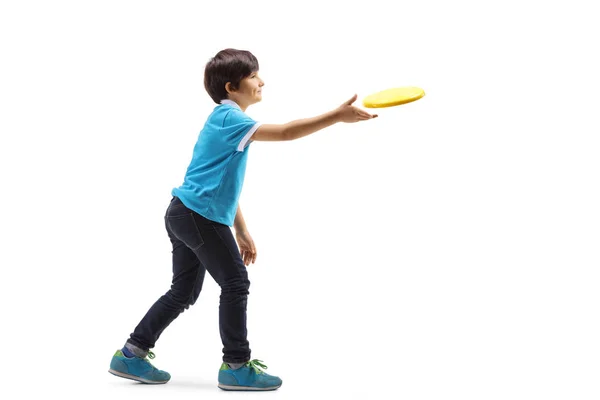 白い背景に孤立したフリスビーを投げる少年のフルレングスプロフィールショット — ストック写真