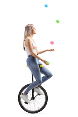 Beyaz arka planda izole bir Unicycle üzerinde topları ile hokkabazlık genç bir kadının tam uzunlukta profil çekim