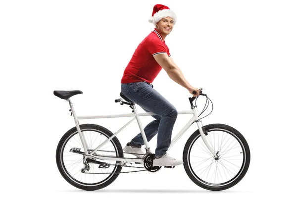 Young man with a christmas hat riding a tandem bicycle and looki — Stock Photo, Image