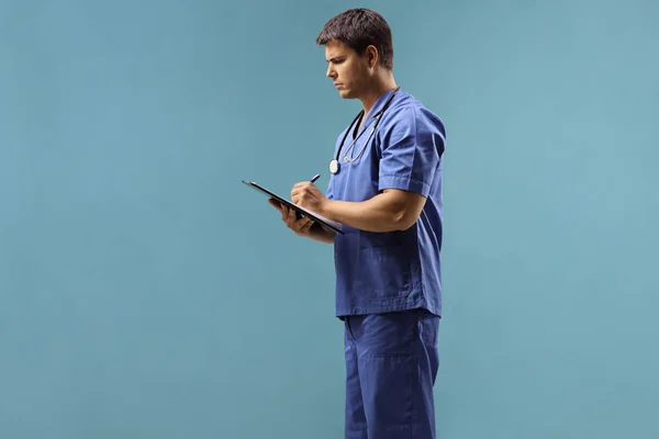 Médico masculino serio escribiendo en un papel — Foto de Stock