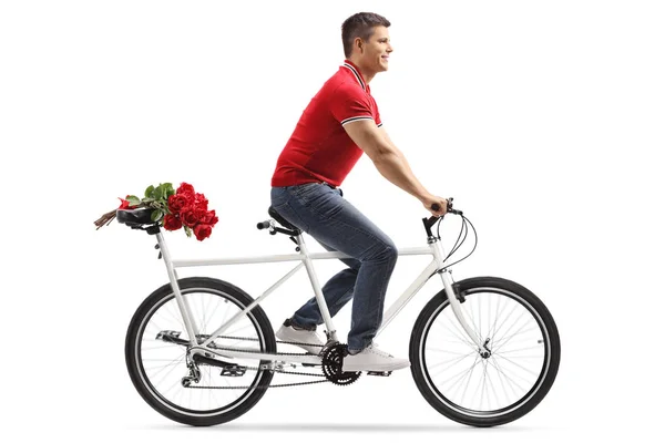 Joven hombre alegre montando una bicicleta en tándem y llevando rosa roja —  Fotos de Stock