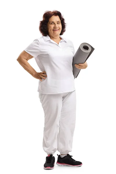 Mujer mayor de pie y sosteniendo una alfombra de ejercicio — Foto de Stock
