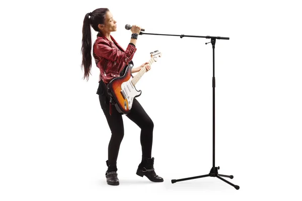 Жіночий рок-музикант з гітарою співає на мікрофоні — стокове фото