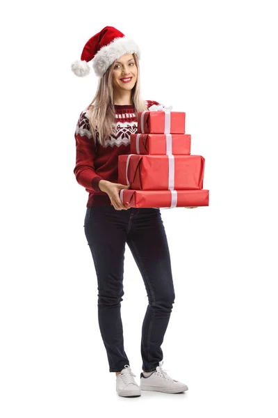 Jonge vrouw met een kerstman hoed met een stapel cadeautjes — Stockfoto