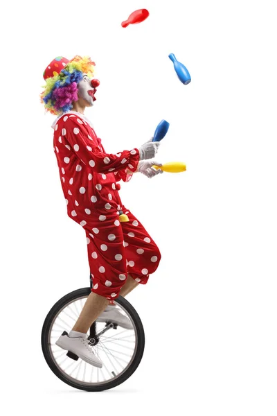 Clown on a unicycle juggling with clubs — Stock Photo, Image