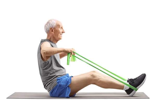 Starszy mężczyzna siedzi i ćwiczenia z elastyczną opaską — Zdjęcie stockowe