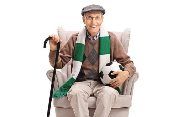 Bir futbol topu ve bir atkı bir koltukta oturan kıdemli adam — Stok fotoğraf
