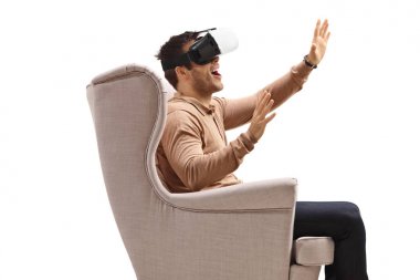 Koltuktaki genç adam sanal gerçeklik kulaklığını izliyor.