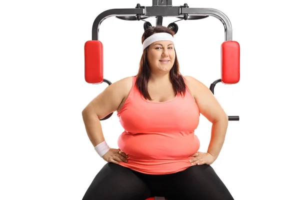 Kilolu kadın bir egzersiz fitness makinesi üzerinde oturan — Stok fotoğraf