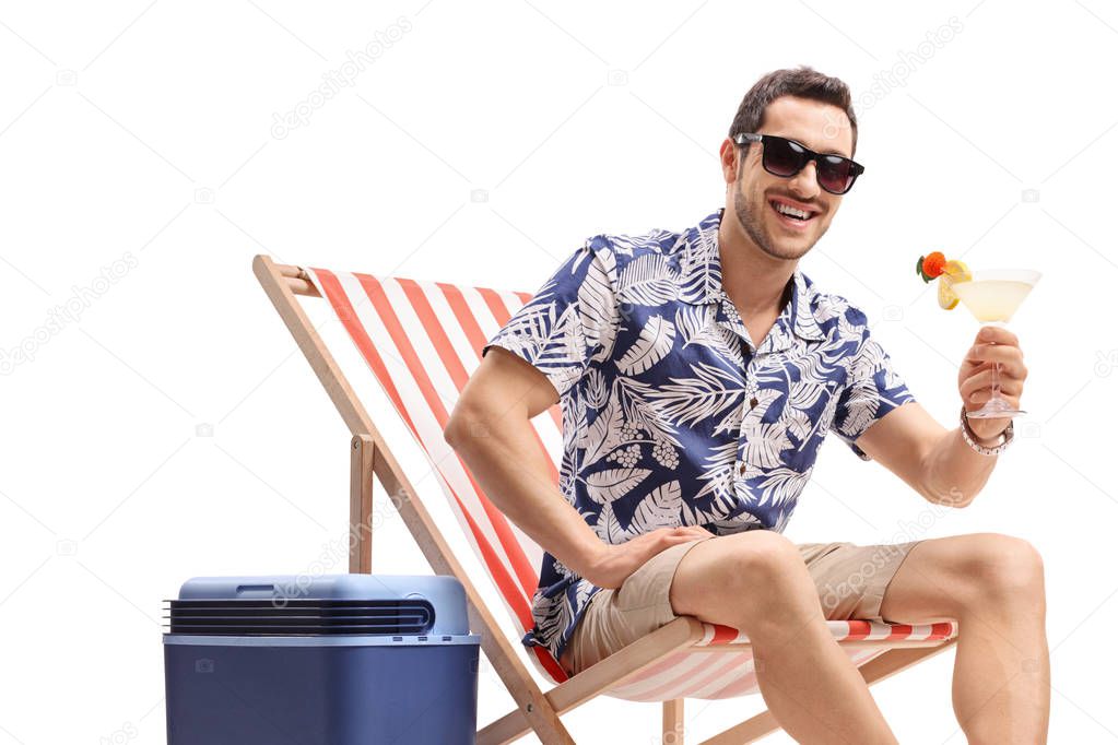 Young guy with a cocktail sitting in a deck chair next to a cool