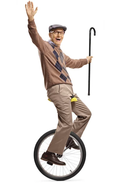 Пожилой человек едет на одноколесном велосипеде и держит трость — стоковое фото