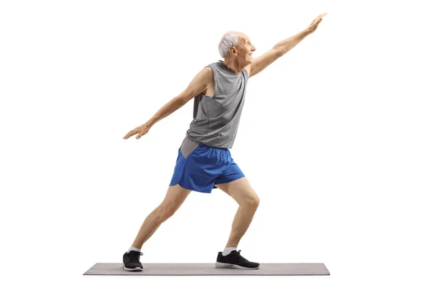 Senior man in sports clothes stretching on an exercise mat — Stock Photo, Image