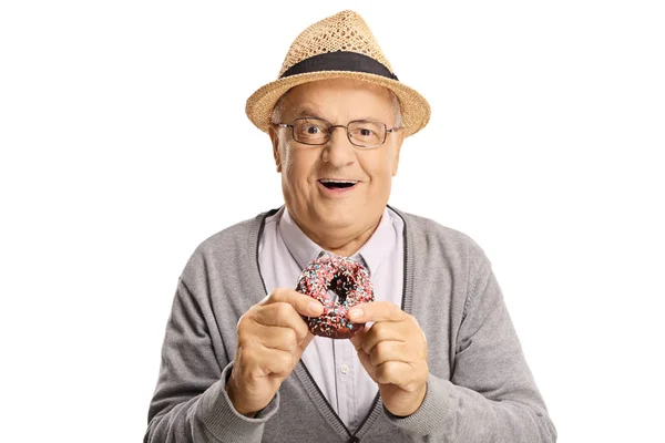 Wesoły starszy mężczyzna jedząc pączek — Zdjęcie stockowe