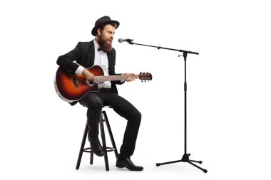 Müzisyen mikrofonda şarkı söylüyor ve akustik gitar çalıyor