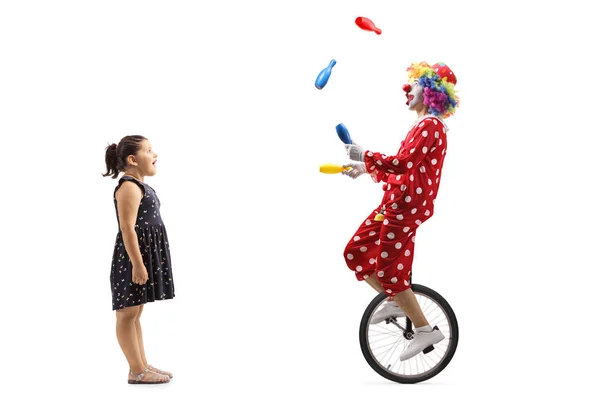 惊讶的小女孩看着一个小丑在独轮车杂耍 — 图库照片