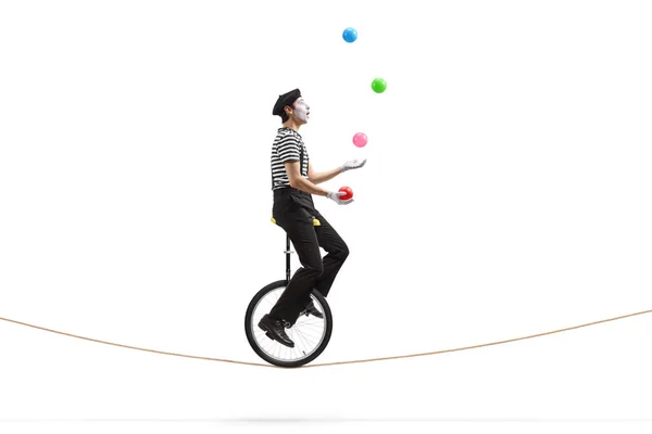 Mime chevauchant un monocycle sur une corde et jonglant avec des balles — Photo