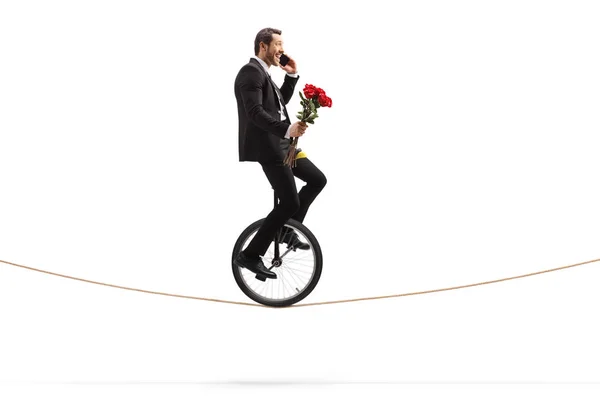 Empresario con rosas hablando por teléfono y montando un monociclo —  Fotos de Stock