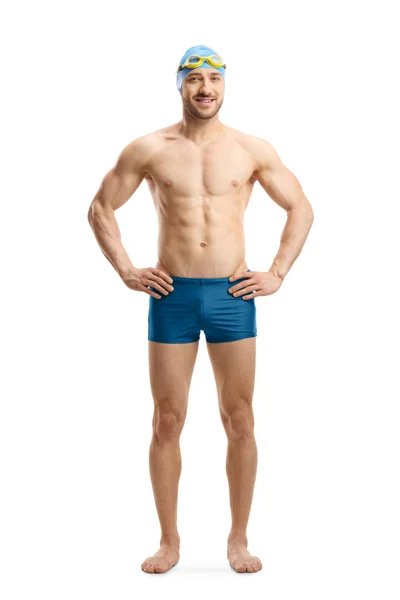 Man in swimming shorts, googles and a cap posing