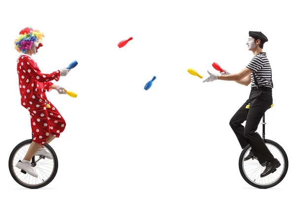 Mimo y payaso en monociclos haciendo malabares con palos —  Fotos de Stock