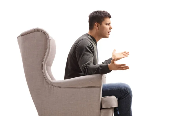 Profile of a young man sitting in an armchair and arguing with s — Stock Photo, Image