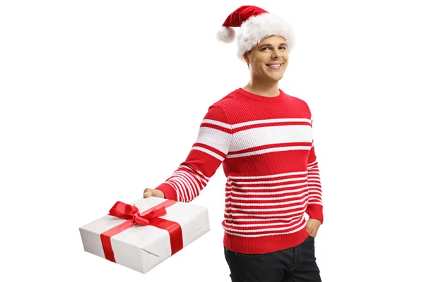 Cheerful young man wearing a santa claus hat and holding a prese — Stock Photo, Image
