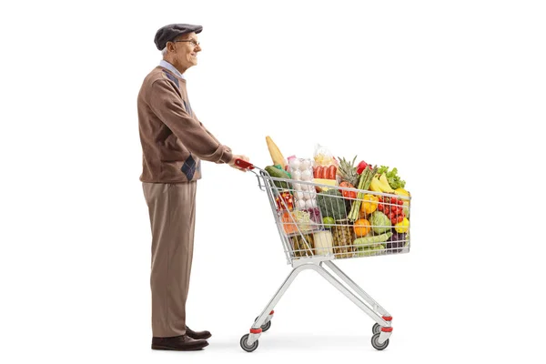 Hombre mayor de pie y esperando con un carrito de compras con comida p —  Fotos de Stock