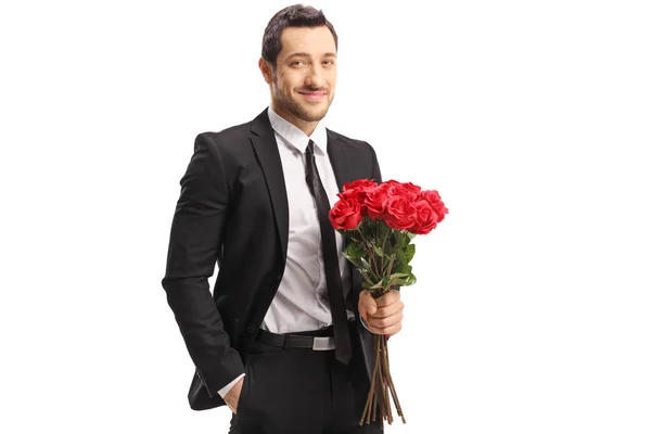 Jeune homme en costume tenant un bouquet de roses rouges — Photo