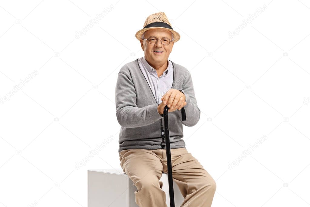 Elderly man with a cane sitting and looking at the camera 