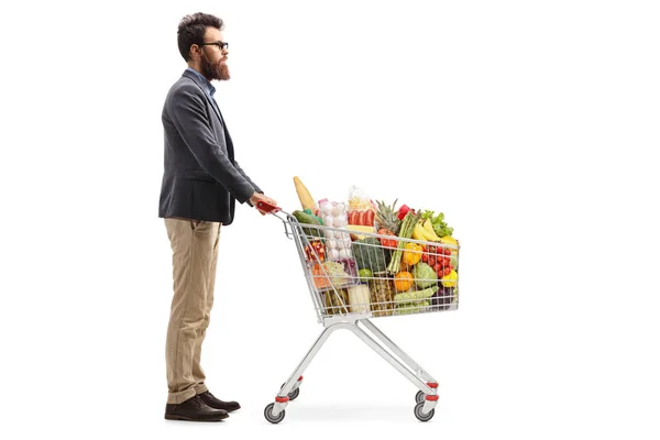Homem barbudo com um carrinho de compras cheio de produtos alimentares — Fotografia de Stock