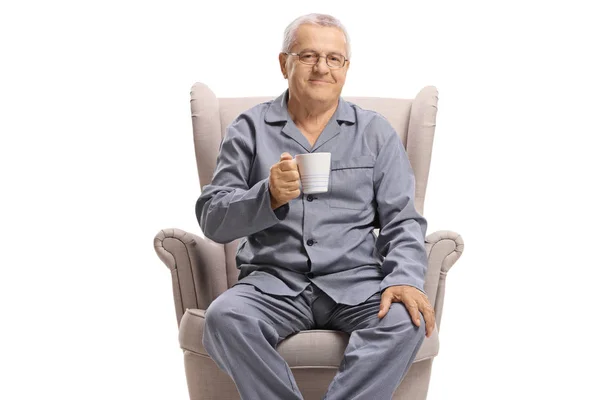 穿着睡衣的老人坐在扶手椅上 拿着一杯热饮 与白色背景隔离 — 图库照片