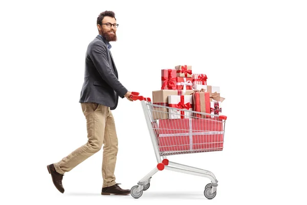 Sakallı Genç Bir Adamın Hediyelerle Dolu Bir Alışveriş Arabasını Iterek — Stok fotoğraf