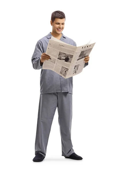 Ung man i pyjamas stående och läsa en tidning — Stockfoto
