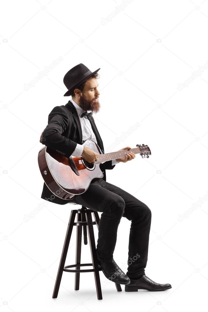 Man sitting on a chair and playing an acoustic guitar
