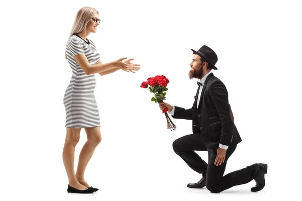 Bearded man kneeling and giving a bouquet of red roses to a woma — Stock Photo, Image