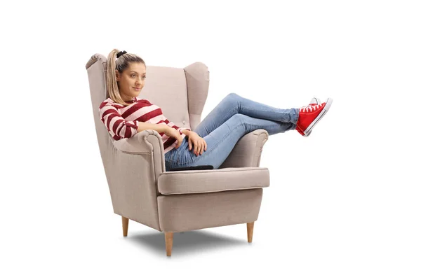 Młoda kobieta siedząca na fotelu oglądając telewizję — Zdjęcie stockowe
