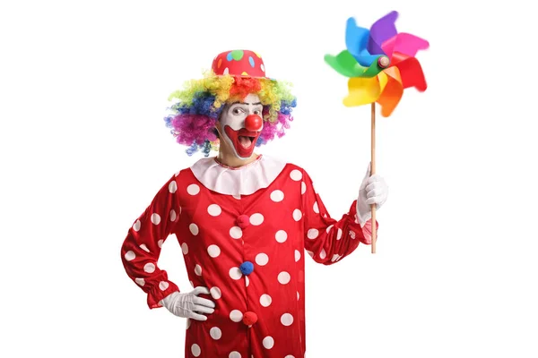 Fröhlicher Clown hält ein buntes Windrad in der Hand und blickt auf die ca. — Stockfoto