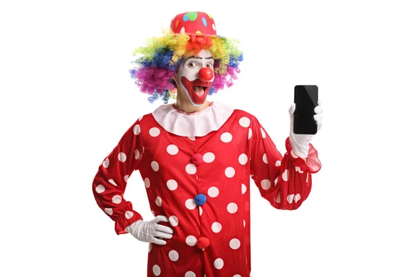 Веселый клоун держит мобильный телефон и смотрит в камеру — стоковое фото