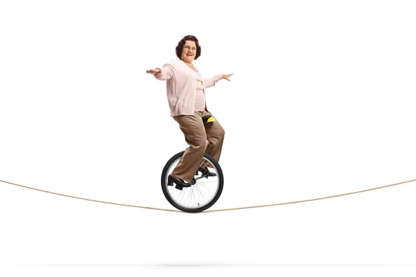 Idosa montando um monociclo em uma corda — Fotografia de Stock