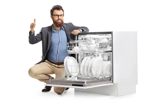 Hombre arrodillado junto a una lavadora de platos y mostrando pulgares u —  Fotos de Stock