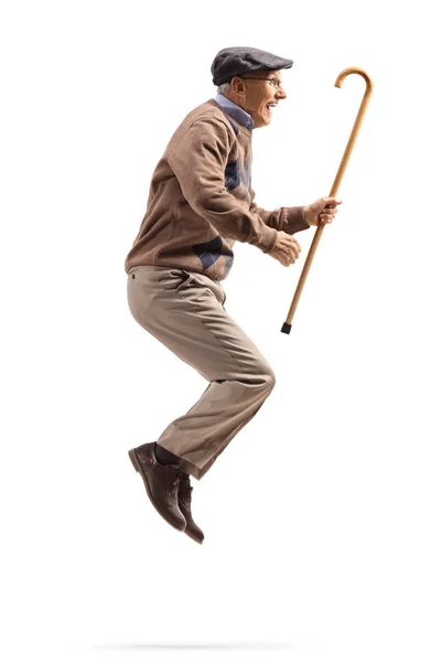 Elderly man jumping and holding a walking cane — Stock Photo, Image