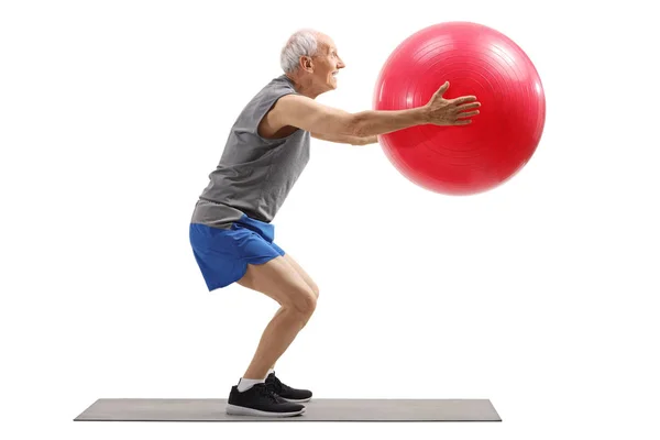 Oudere man trainen met een fitness bal op een mat — Stockfoto