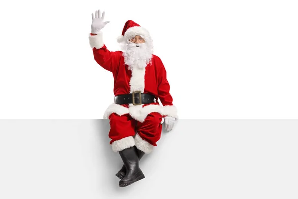 Санта Клаус сидит на панели и машет — стоковое фото