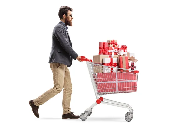 Bearded man pushing a shopping cart full of presents — Stock Photo, Image