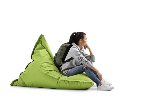 Wanita muda dengan ransel duduk di atas kantong kacang hijau — Stok Foto