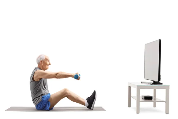 Yaşlı adam bir Tv önünde dambıl ile egzersiz — Stok fotoğraf