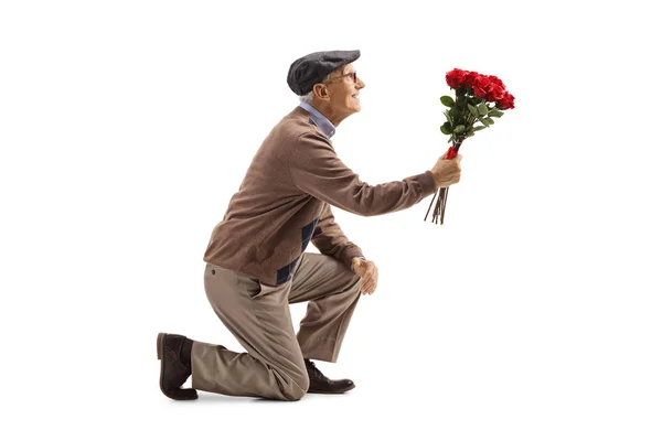 Senior man knielende met een boeket van rozen — Stockfoto