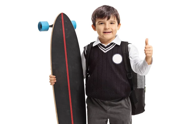 Little schoolboy with a longboard making a thumb up sign — Stock Photo, Image