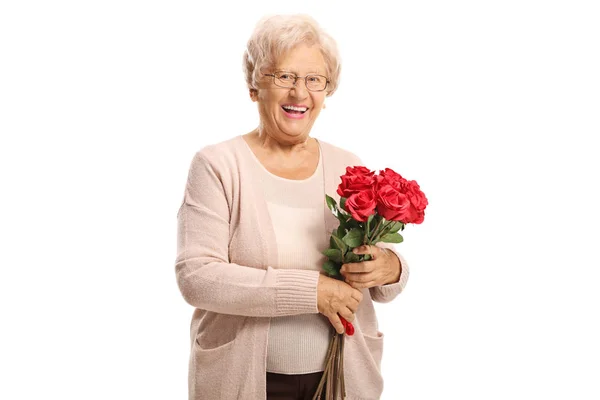 Cheerful elderly woman holding a bouquet of red roses and smilin — Stock Photo, Image