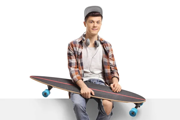 Male skater with a longboard sitting on a panel — Stock Photo, Image